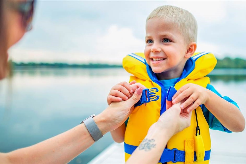 parent puts on life jacket on their kid